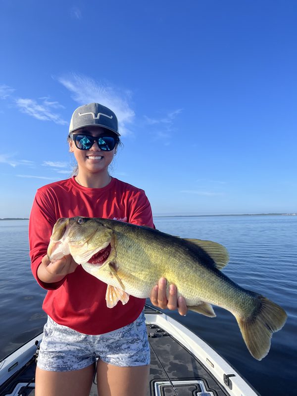 Woman angler holding a long largemouth bass on a bass boat